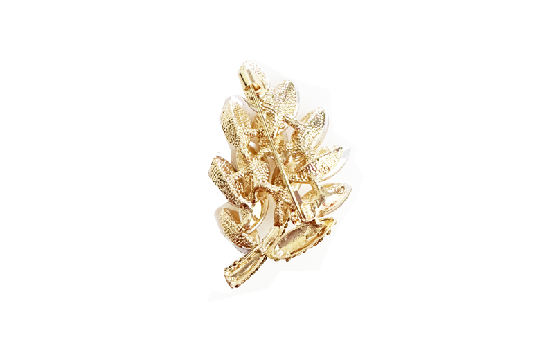 Broche in goudkleurig metaal met champagnekleurige stenen in bladvorm, achterkant van de Champagne Tree met de speld