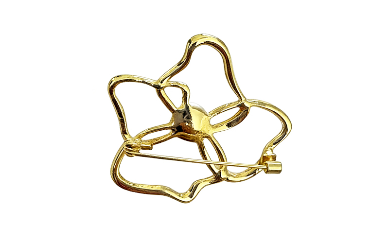 Broche in goudkleur met parelkleurige kraal, achterkant met speld