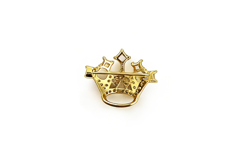Broche in goudkleur met heldere stenen, achterkant met speld