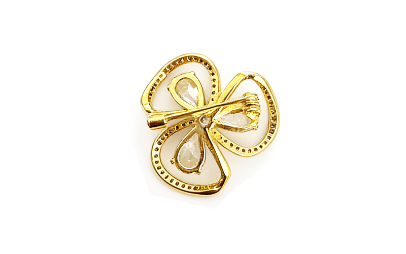 Broche in goudkleur met druppelstenen, achterkant met speld